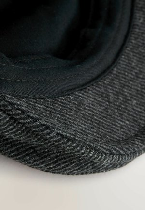 Grauer texturierter Stoff mit einem glatten, schwarzen Innenfutter. Gewölbter Schirm und weiche Kanten. Hat subtile Muster auf der Oberfläche.