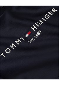 Felpa navy con logo ricamato "TOMMY HILFIGER" e anno di fondazione "EST. 1985" in bianco, con un accento di colore rosso, bianco e blu nel logo.