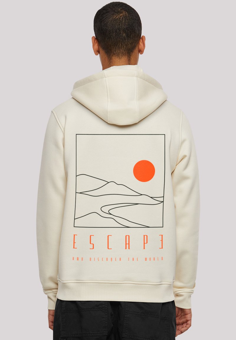 Sweatshirt crème avec un design graphique de montagnes et d'un soleil orange. Le texte en dessous dit "ÉVADER ET DÉCOUVRIR LE MONDE."
