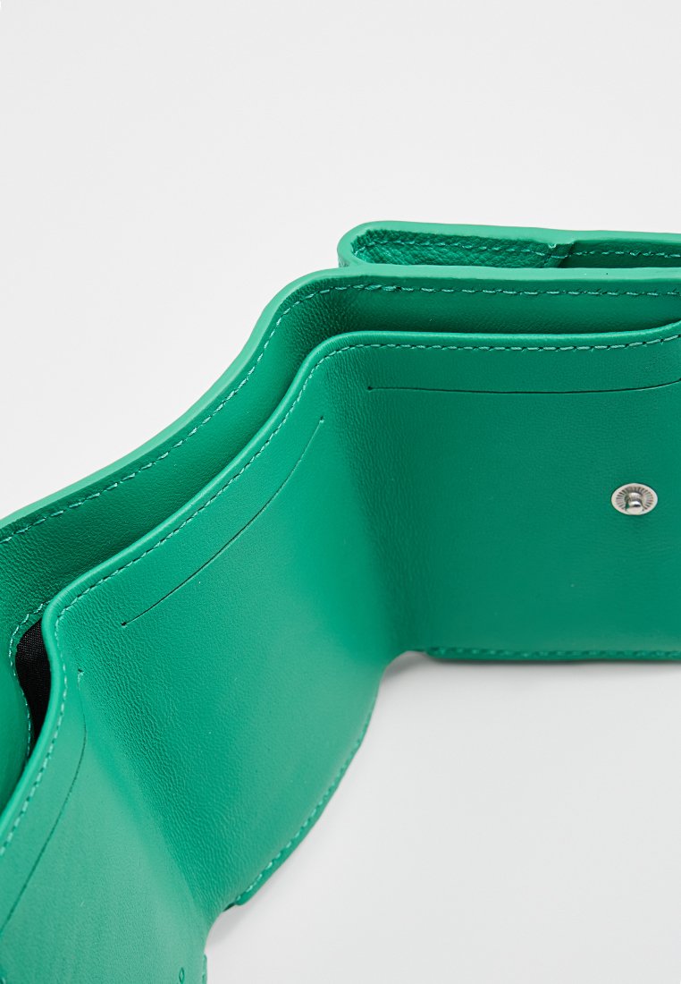 Grünes Lederportemonnaie mit mehreren Fächern, glatter Textur, kontrastierendem schwarzen Innenraum und einem Druckverschlussdetail.