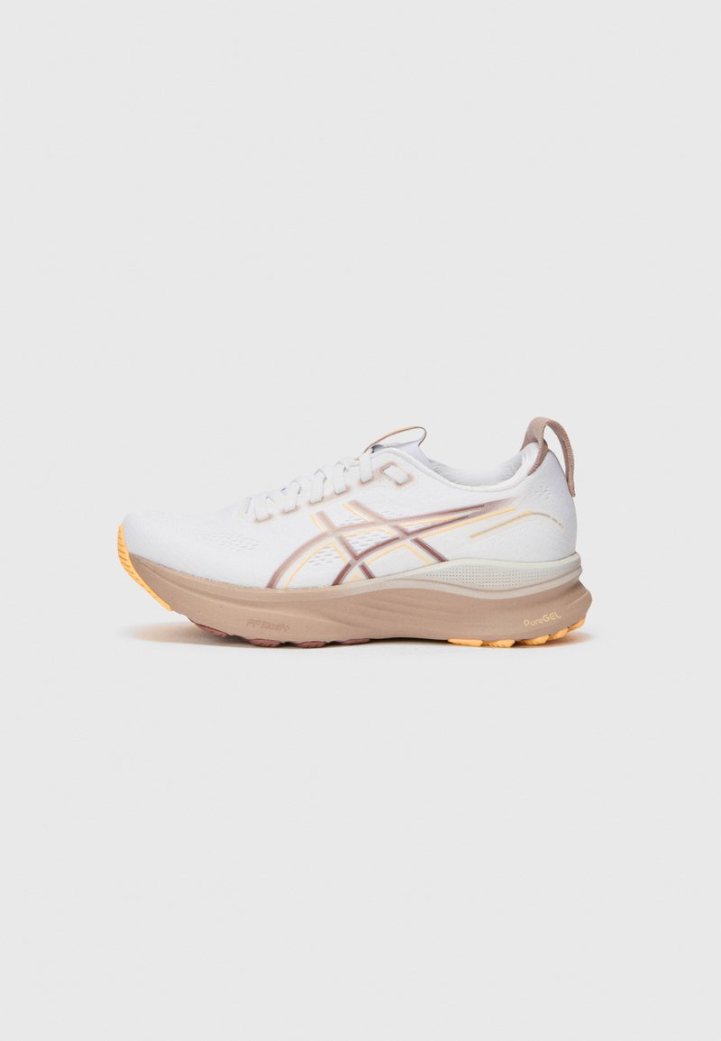Weiße Sportschuhe mit beigen Akzenten, strukturiertem Obermaterial, Schnürsystem und orangefarbener Sohle. Besitzt gestalterische Linien an den Seiten für zusätzliche Details.