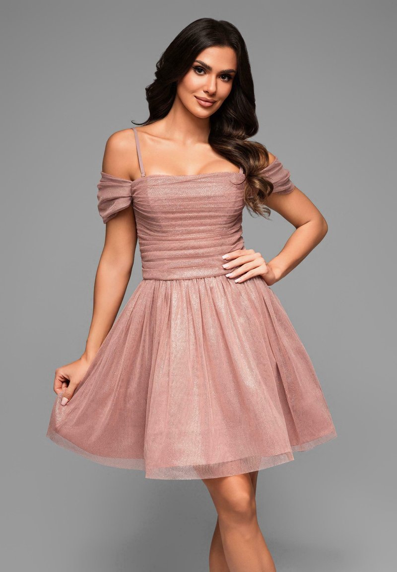 Robe en tulle rose avec un corsage ajusté et des manches dénudées. Présente des fronces et une jupe évasée, ajoutant du volume et de la texture.