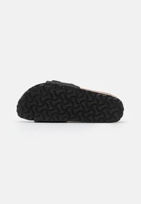 Black rubber sandal sole with wave-patterned tread; features a cork-like midsole. Minimalist design suitable for casual wear.