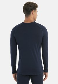 Navy long-sleeve shirt with a fitted shape and ribbed texture. Features raglan sleeves and a rounded neckline. Soft, stretchy material.