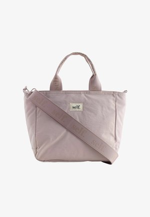 Light pink tote bag with two short handles, a wide adjustable shoulder strap, and "self." logo on front panel and strap.