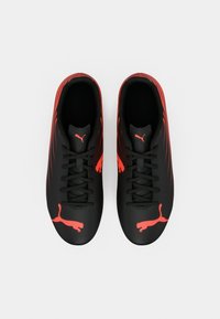 Ζευγάρι από αθλητικά παπούτσια Puma, μαύρα και κόκκινα με κορδόνια, φωτογραφημένα από πάνω σε απλό λευκό φόντο.