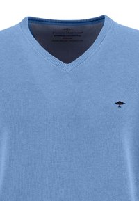 Maglione azzurro chiaro a V in cotone, presenta una texture a maglia fine e un piccolo logo ricamato sul lato sinistro del petto.