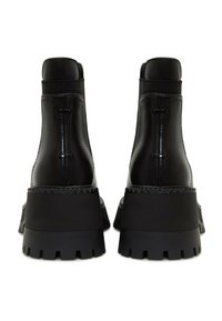 Paire de bottines à plateforme en cuir noir avec semelles crantées épaisses, coutures visibles et panneaux latéraux élastiques, vues de dos.