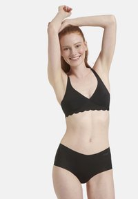 Schwarzer Bralette mit gewelltem Saum und passenden hochgeschnittenen Shorts. Hergestellt aus glattem, dehnbarem Stoff mit matter Oberfläche.