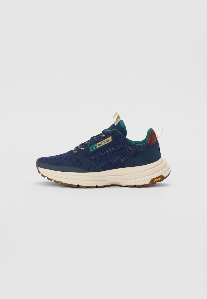 Chaussure de sport bleu marine en matériaux mesh et suède, épaisse semelle intermédiaire blanche, accents contrastants verts et bordeaux, et semelle extérieure Vibram.
