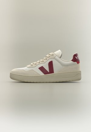 Άσπρο και μπεζ χαμηλό sneaker με κόκκινο λογότυπο "V" στο πλάι και κόκκινη ταμπέλα στη φτέρνα, ανοιχτό μπεζ σόλα και λευκά κορδόνια.