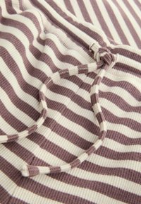 Stribet stof i mauve og creme, med et tekstureret ribbestruktur. Inkluderer en matchende snor detalje.