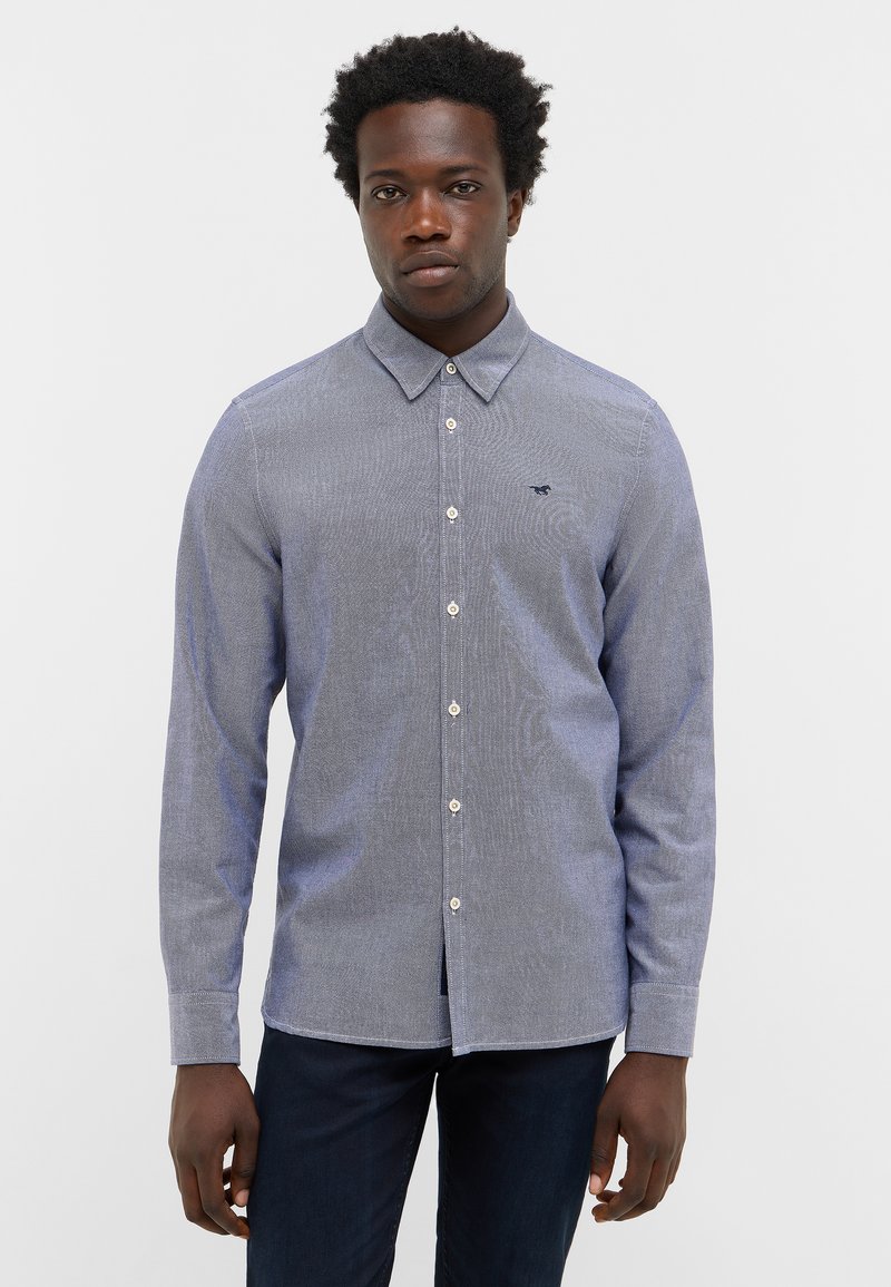 Blau gemusterte Bluse mit Kragen, langen Ärmeln und einem subtil strukturierten Stoff. Verfügt über sichtbare Knöpfe und ein kleines Logo.