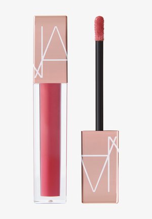 Colore labbra liquido in tubo trasparente, tonalità rosa intenso. Tappo rettangolare color oro rosa con motivo geometrico bianco. Include un applicatore a pennello.