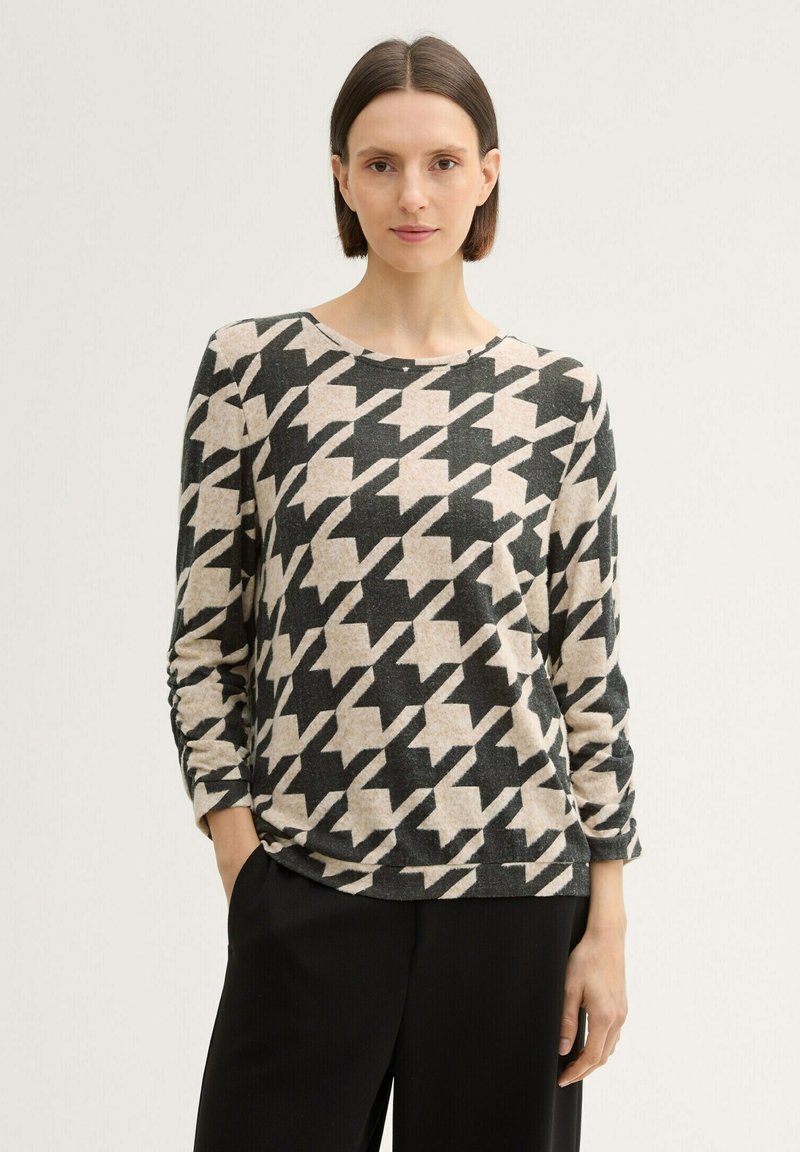 Blusa de punto de manga larga con un patrón de espiga en negro y crema. Textura suave y corte relajado, cuello redondo y mangas ligeramente fruncidas.