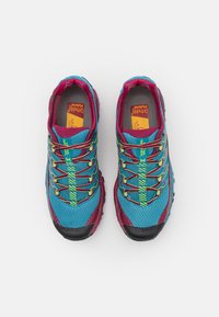 Ténis de atletismo azuis e bordô com um upper de malha texturizada. Apresenta cordões coloridos e uma sola de borracha preta. Marcados com o nome da marca "La Sportiva."