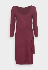Vestido burgundy com mangas longas, decote redondeado e design envolvente com um laço de lado e uma bainha ligeiramente assimétrica. Textura suave.