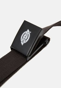 Brun vävt tygbälte med en svart metallspänne som har Dickies-logotypen, vilket framhäver en enkel design och hållbar textur.