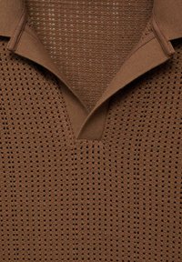 Brown short-sleeve polo with a textured knit design featuring small holes, a v-neck, and a ribbed collar. Lightweight and breathable.