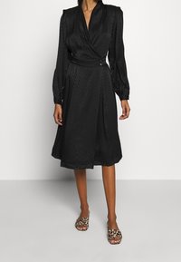 Musta kietaisumekko, jossa on sebraraidoitus, pitkät puffikäsivarret ja vyö vyötäröllä. Yhdistetty leopardikuosisilla liukuvailla sandaaleilla.