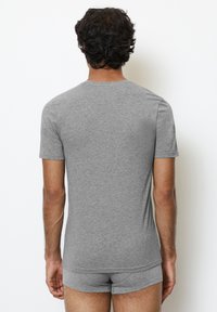Grijze katoenen T-shirt met korte mouwen, voorzien van een ronde hals. De stof lijkt zacht met een gladde textuur. Draagt met bijpassende grijze onderbroek.