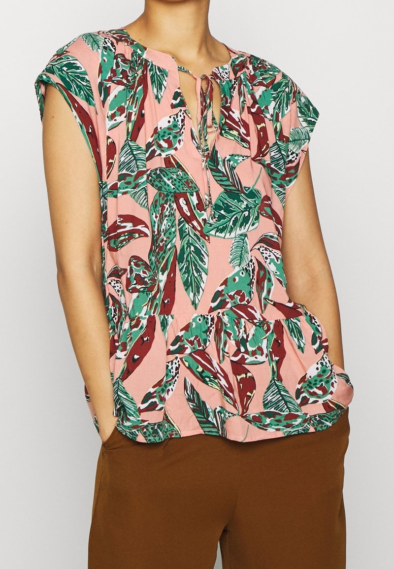 Blusa rosa a maniche corte con un motivo verde e rosso a foglie, caratterizzata da un collo arricciato con un dettaglio a laccio e una vestibilità rilassata.