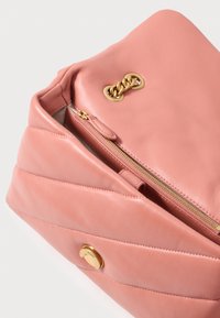 Rózsaszín bőr kézi táska, steppelt mintával, arany színű fém kiegészítőkkel, felső cipzáros záródással és egy kis elülső csattal. A belső része világos bélésű.