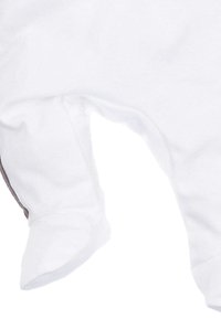 Witte babyslaapzak met voetjes en zichtbare naden op een zachte achtergrond van stof.