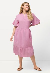 Rosa, strukturiertes Kleid mit V-Ausschnitt, kurzen, schwingenden Ärmeln und einem gestuften Rock. Es hat einen lockeren Schnitt und eine knieumspielende Länge.