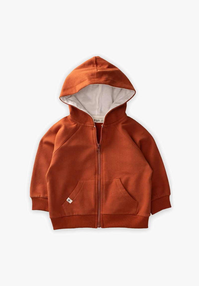 Hrdzavo-oranžová zipová bunda s bielou líniou na kapucni, rebrovanými manžetami a prednými vreckami. Obsahuje malú nálepku na dolnom vrecku. Materiál z bavlnenej zmesi.