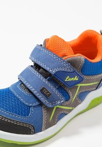 Zapatillas para niños en azul y gris con forro naranja, detalles en verde, dos correas de velcro y la marca "Lurchi" en el costado y la suela.