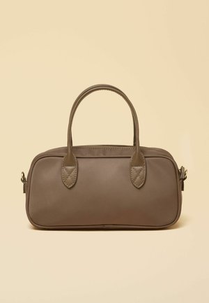 Pruun ristkülikukujuline käekott ümarate servadega, pealmise tõmblukuga, kahe õmmeldud sangaga ja metallist kinnitusdetailidega beeži tausta vastu.