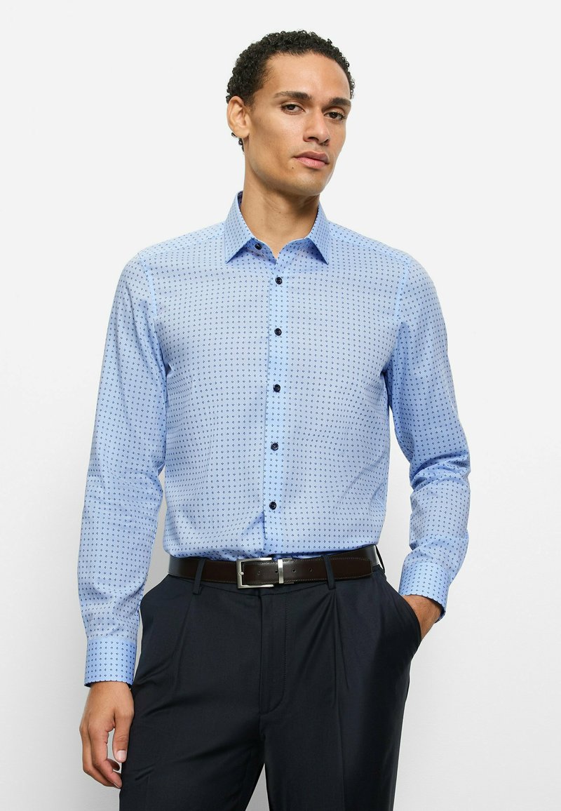 Hellblaues Hemd mit Knopfleiste, kleinem Rautenmuster, langen Ärmeln und dunklen Knöpfen. Kombiniert mit dunkler Hose und braunem Gürtel.