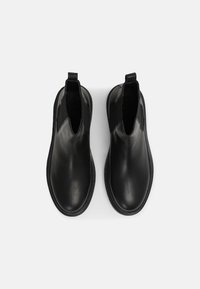 Botas Chelsea de cuero negro con paneles laterales elásticos y tiradores, que presentan un acabado suave y un diseño de punta redonda.