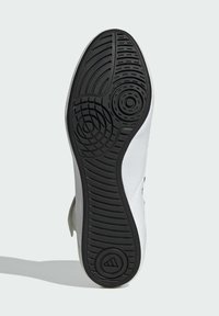 White athletic shoe sole with textured black rubber. Features include circular patterns and grooves for traction, with a logo detailing.