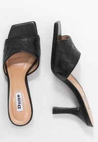 Mules negros de punta abierta con parte superior de cuero trenzado, punta cuadrada y tacón alto y delgado. Presentan una plantilla en tono nude con la marca "Dune London".