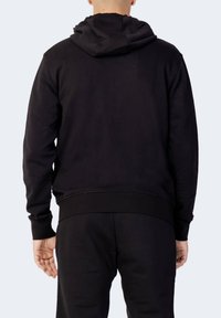 Sweatshirt noir à capuche avec une texture douce, poche kangourou et poignets et ourlet côtelés. Le tissu semble durable et extensible.