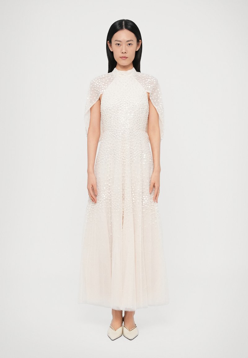 Dlhé svetlo slonovinové šaty s textúrovanou, bodkovanou látkou. Majú vysoký golier a pláštenkové rukávy. Nosia sa s bielymi, špicatými topánkami.