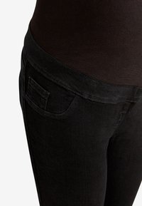 Mustat denim-farkut, joissa on korkea vyötärö, takatasku ja pehmeä, sileä pinta. Suunnittelu on slim fit ja tyylikäs.