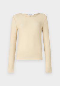 Langermet topp i myk, glatt beige stoff. Har rund hals og et tettsittende design. Minimalistisk uten merkbare mønstre eller detaljer.
