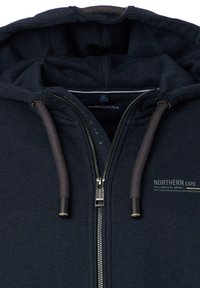 Navyblaue Zip-Hoodie mit weicher Textur, ausgestattet mit einer Kordelzugkapuze, einem metallischen Reißverschluss und einem bedruckten Logo auf der linken Brust.