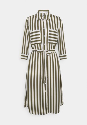 Pruhovaná košilová šaty v tmavě olivové a bílé barvě. Má límečkový výstřih, dlouhé rukávy, dvě náprsní kapsy a detail vázání v pase.