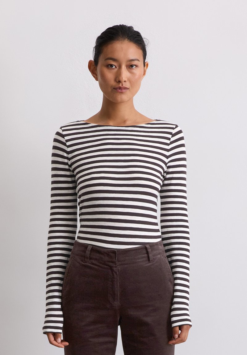 Langsleeve gestreepte top in wit en bruin met een bootnek. Gecombineerd met donkerbruine corduroy broek. De stof ziet er glad en aansluitend uit.