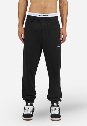 Sorte sweatpants med elastisk talje og manchetter, med et hvidt "PEGADOR" logo på venstre lår. Fremstillet af blødt, glat stof.