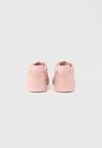 Ζευγάρι ανοιχτό ροζ sneakers χαμηλού κόστους με παχύ πέλμα, εμφανιζόμενα από πίσω πάνω σε απλό ανοιχτό γκρι φόντο.