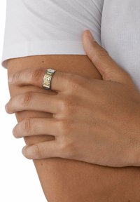 Silverfärgad metallring med graverad "DIESEL" i gult. Slät yta, rund design och en lätt avsmalnande form.