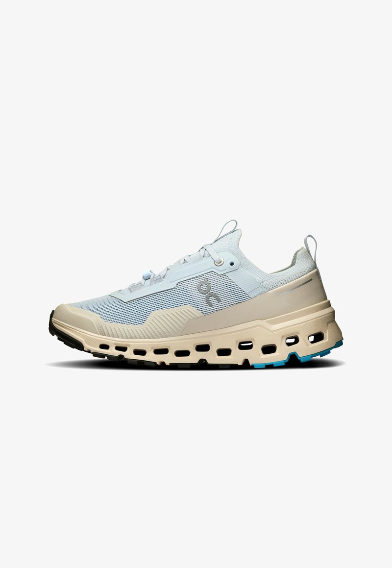 Baskets de sport bleu clair et beige avec dessus en mesh respirant, fermeture à lacets et semelle épaisse et rembourrée avec plusieurs trous d’aération.