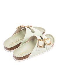 Sandalias verde menta con dos hebillas doradas, planta de corcho y suela de goma blanca. Presenta un diseño tipo thong y un forro suave y texturizado.