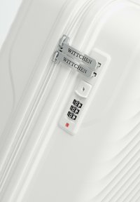 White hard-shell suitcase with textured wavy design, dual zipper, and a combination lock featuring a red button and numeric dials.