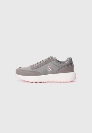 Grå sneakers med en teksturert overflate, rosa detaljer på sålen og hvit mellomsåle. Har en rund tå og snørelukking.